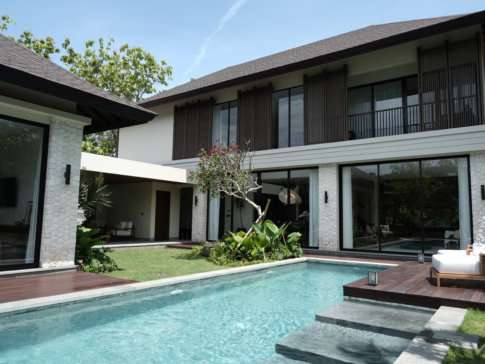 Pool and timber deck at the back of the villa, with the two-storey louvred facade behind